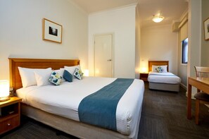 Une chambre d’hôtel avec un grand lit, un lit plus petit, un bureau et une chaise.