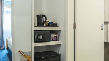 A hotel room with a microwave, coffee maker, and a small refrigerator on a white shelf.
