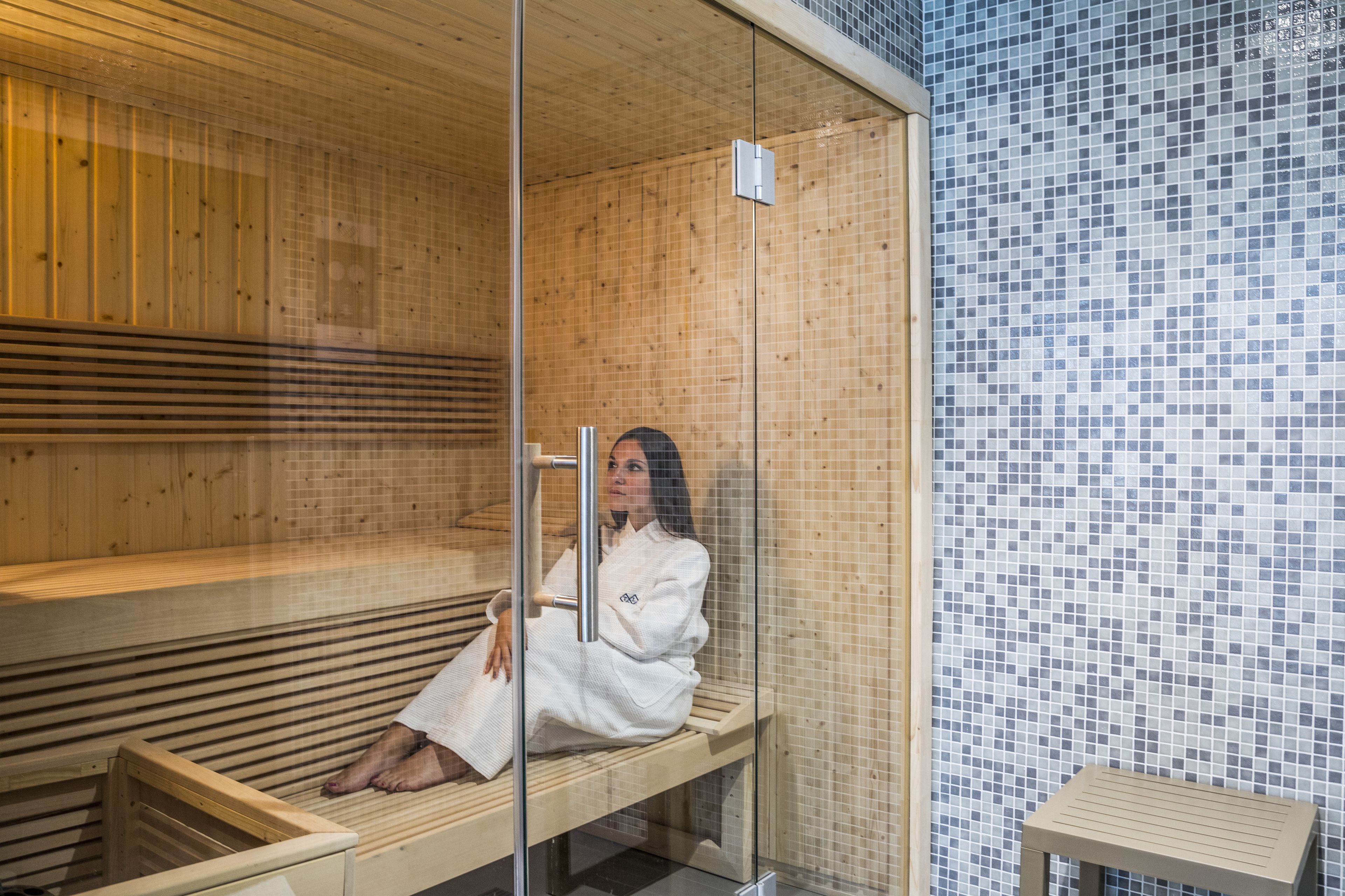 A sauna with wooden benches and a glass partition.