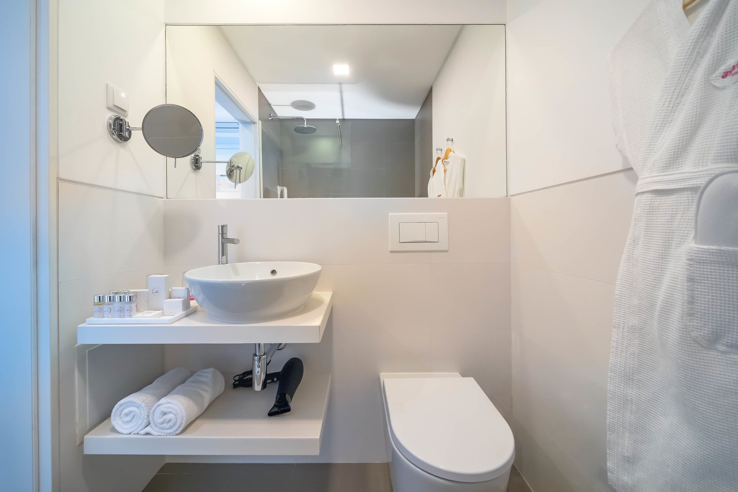 Ein modernes Badezimmer mit Waschbecken, Spiegel und Toilette in Weiß.