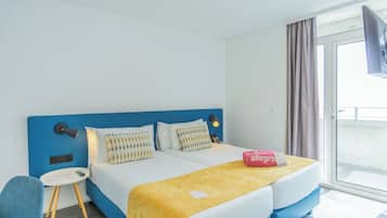 Habitación de hotel con dos camas, una mesita, una silla y un televisor.