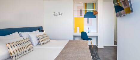 Una habitación de hotel moderna con una cama, un escritorio, una silla y un televisor fijado a la pared.