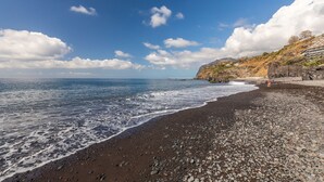 Una playa con costa rocosa y cielo despejado.