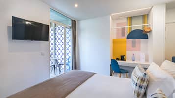 A modern hotel room with a bed, a desk, a chair, and a television.