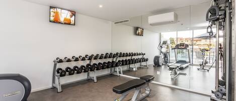 Une salle de sport équipée de tapis de course, d’haltères et d’appareils de musculation.