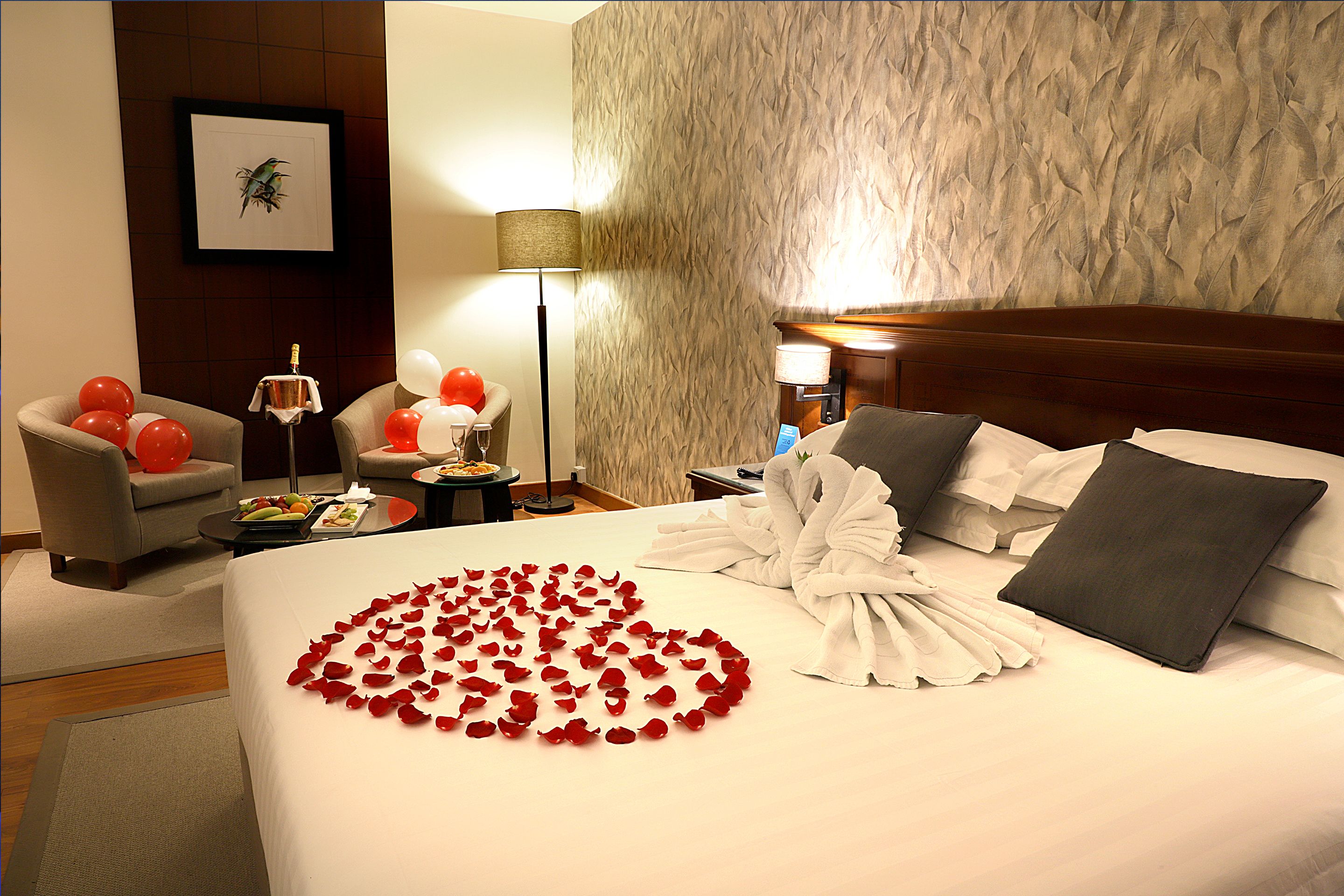 Une chambre d’hôtel avec un lit bien fait, une chaise, une table avec de la nourriture et une lampe.
