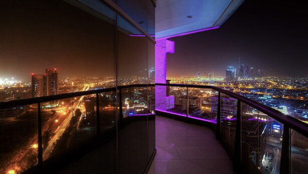 Vista nocturna desde un balcón con un paisaje urbano al fondo.
