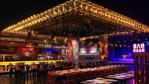 Zona de bar con mesas y sillas, una barra con botellas, y un cartel que dice 'BAR HAAR'.