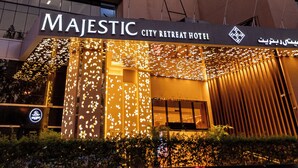 Un hotel moderno con fachada curva, varias banderas y una entrada bien iluminada.