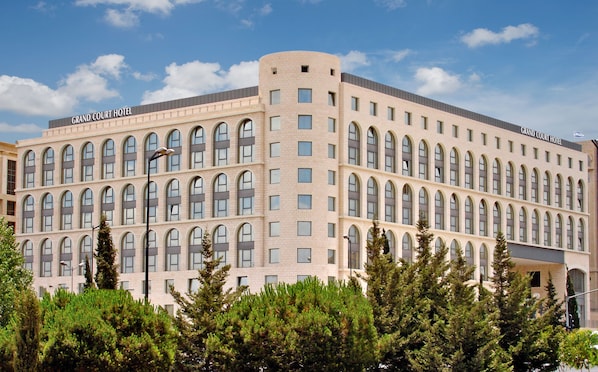 Un hotel grande de varios pisos con fachada simétrica, numerosas ventanas y una esquina curva destacada.