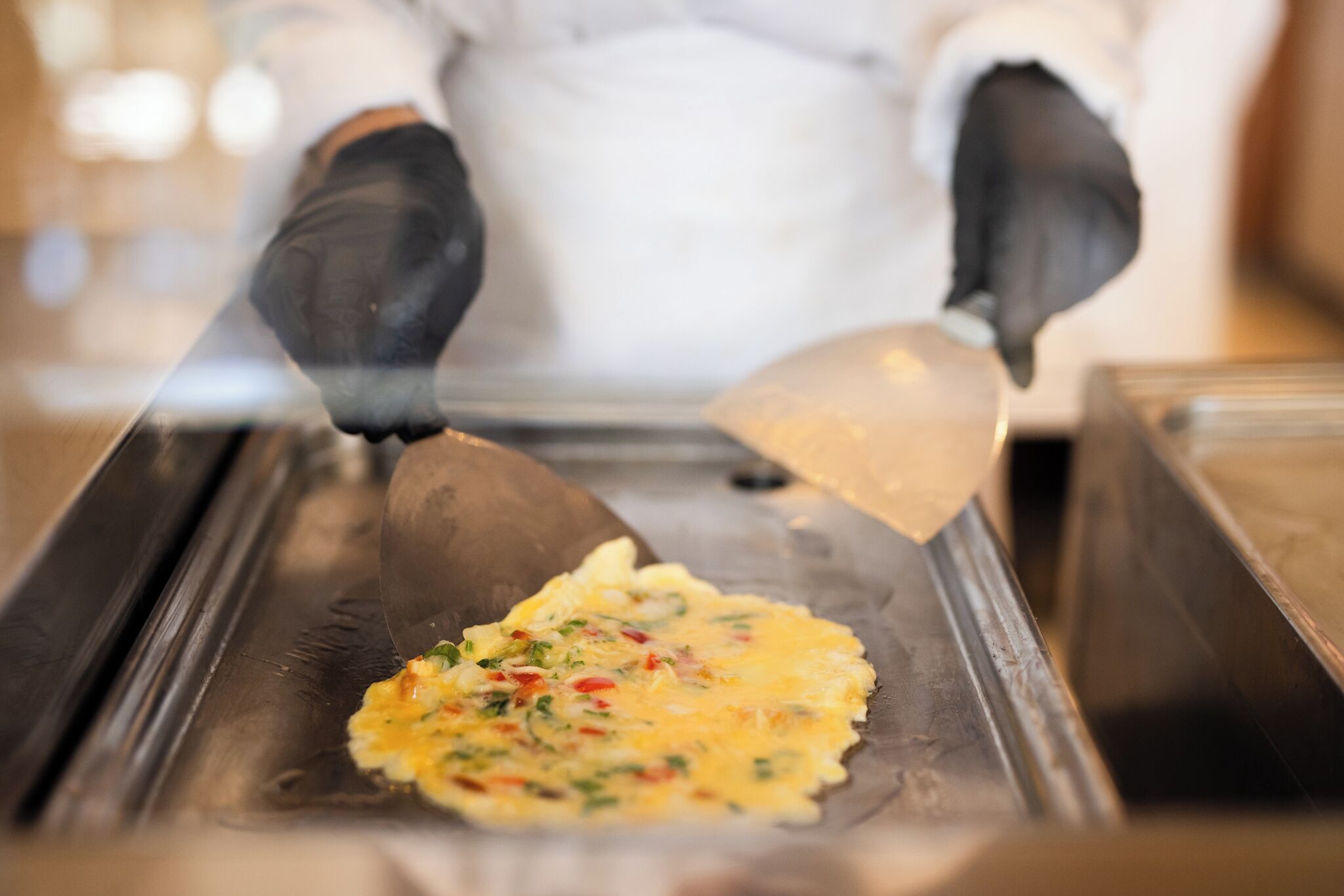 Un cocinero preparando un plato sobre una plancha caliente.