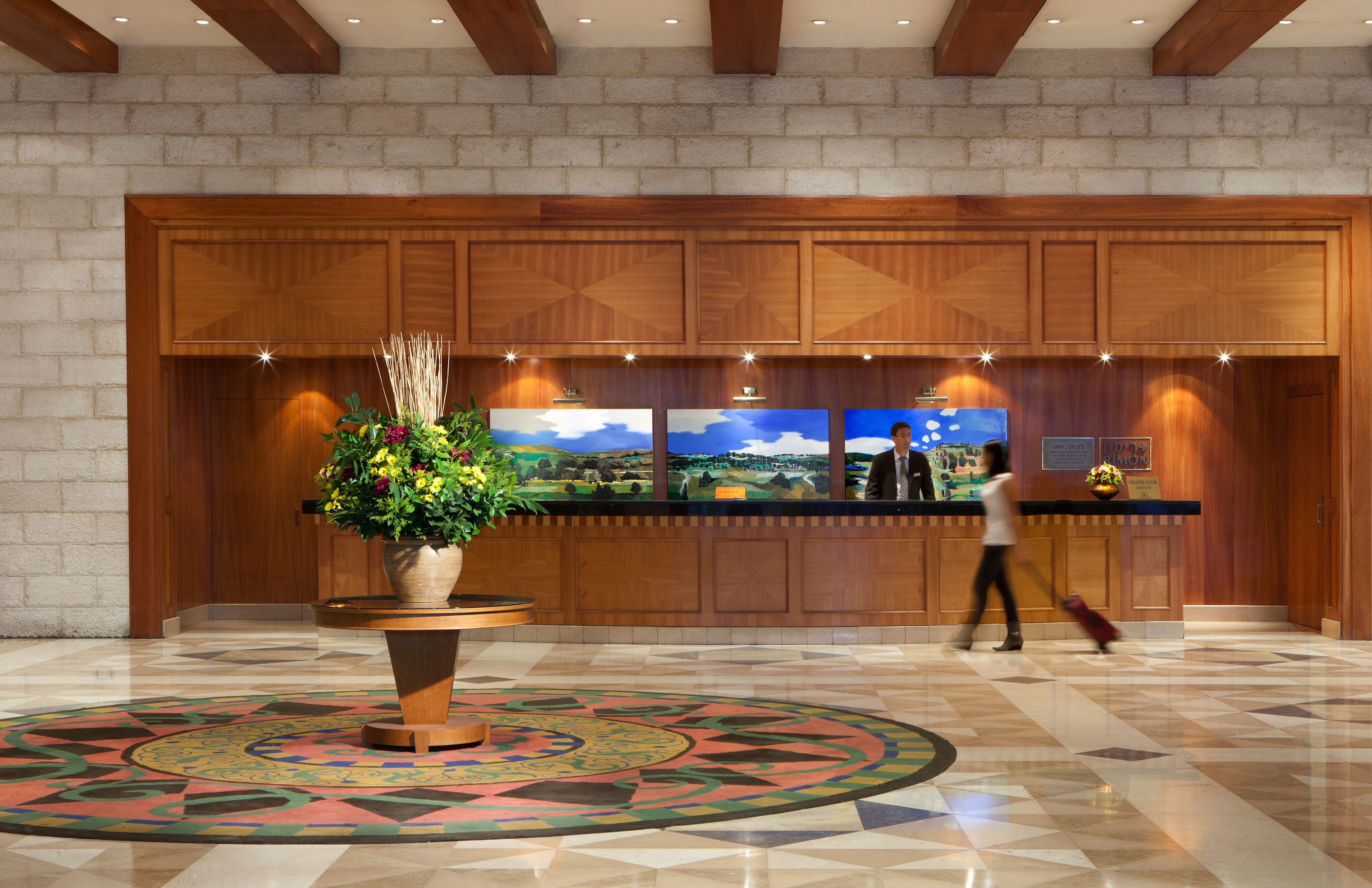 A lobby with a reception desk, a large potted plant, and a patterned carpet.