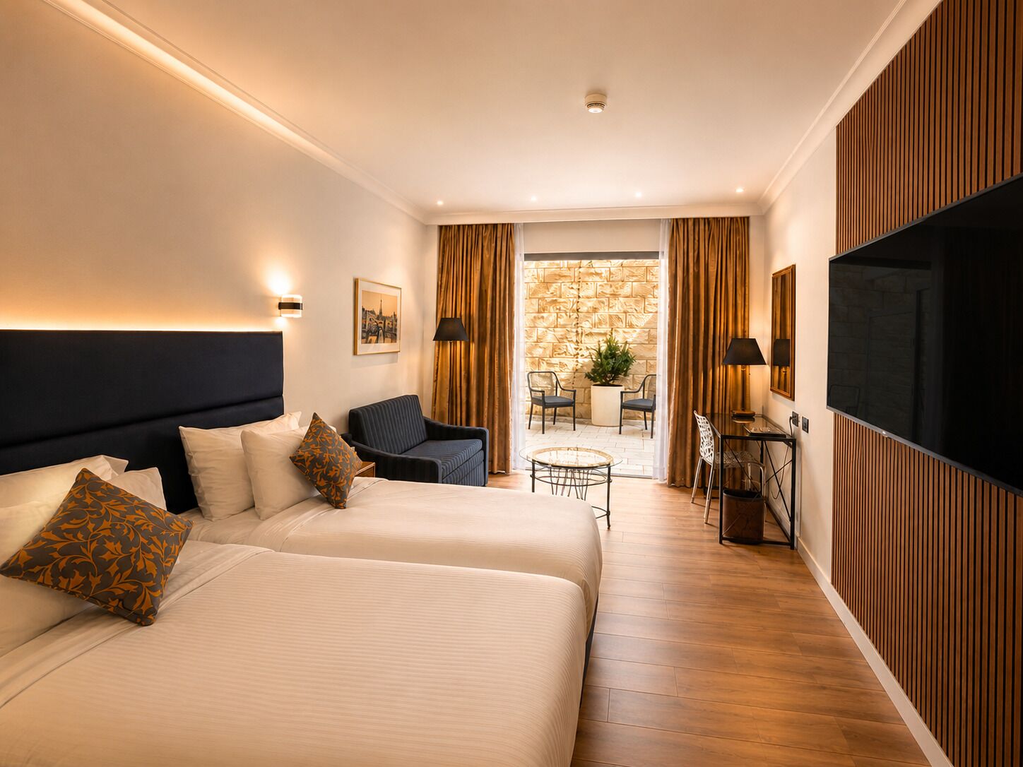 Habitación de hotel con dos camas, un escritorio, una silla, un televisor y vistas al exterior.