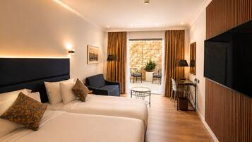Habitación de hotel con dos camas, un escritorio, una silla, un televisor y vistas al exterior.