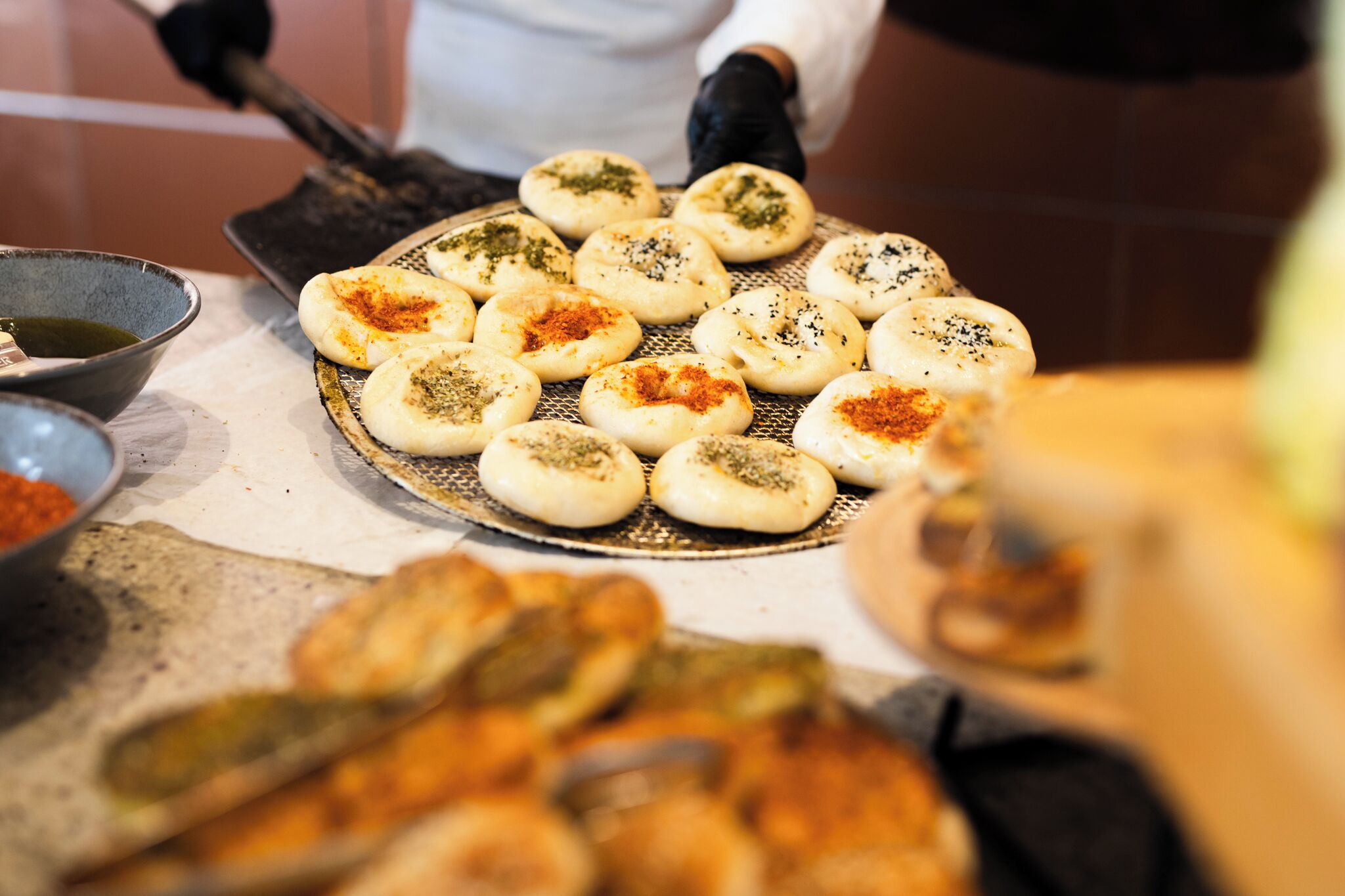 Una zona de cocina con una plancha, una persona con delantal blanco y diversos alimentos en preparación.