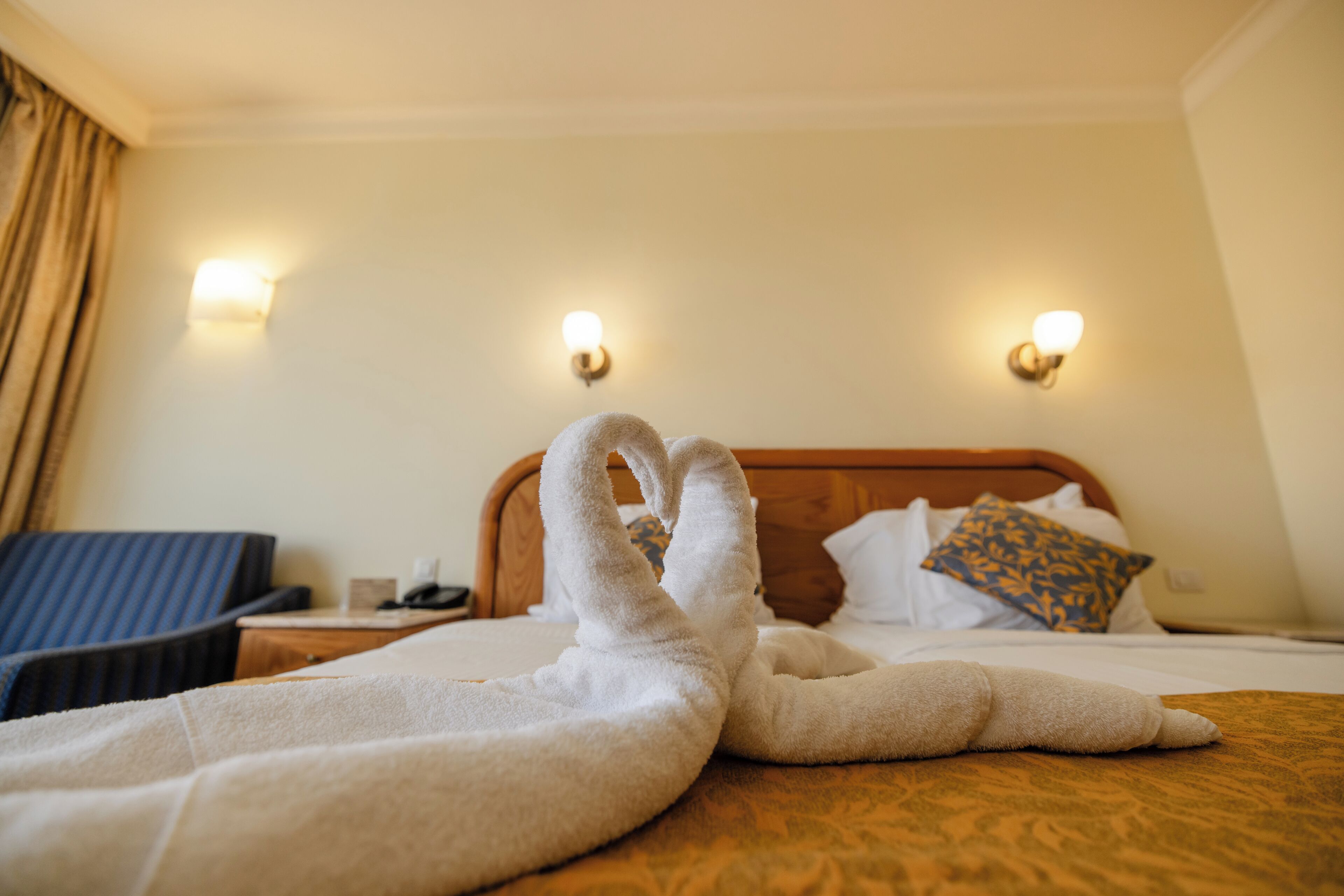 Une chambre d’hôtel avec un lit bien fait, une tête de lit en bois et deux appliques murales.