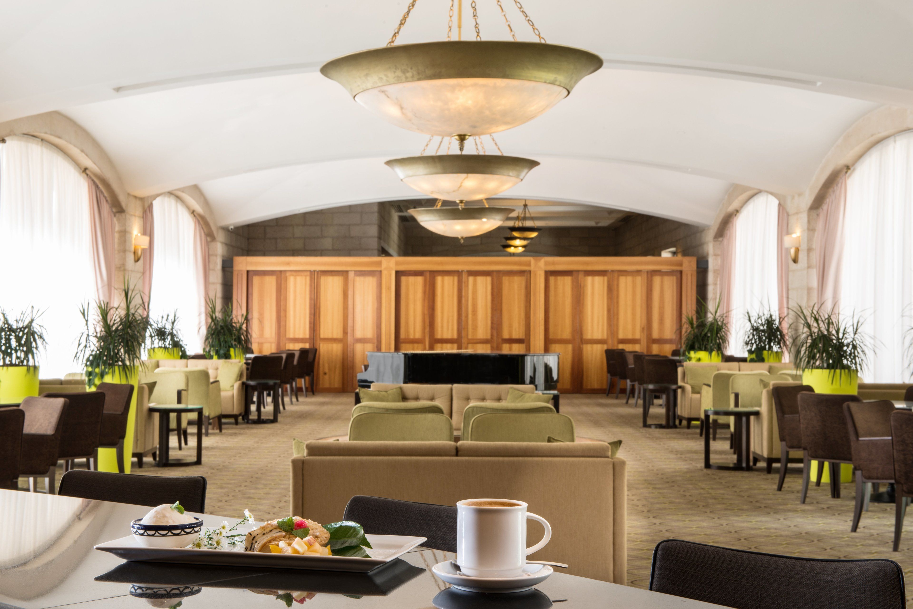 A spacious hotel lobby with a large seating area, a television, and a coffee table with a plate of food and a cup of coffee.