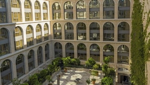 Un patio con varios niveles de ventanas arqueadas, plantas en macetas y zonas de estar al aire libre.