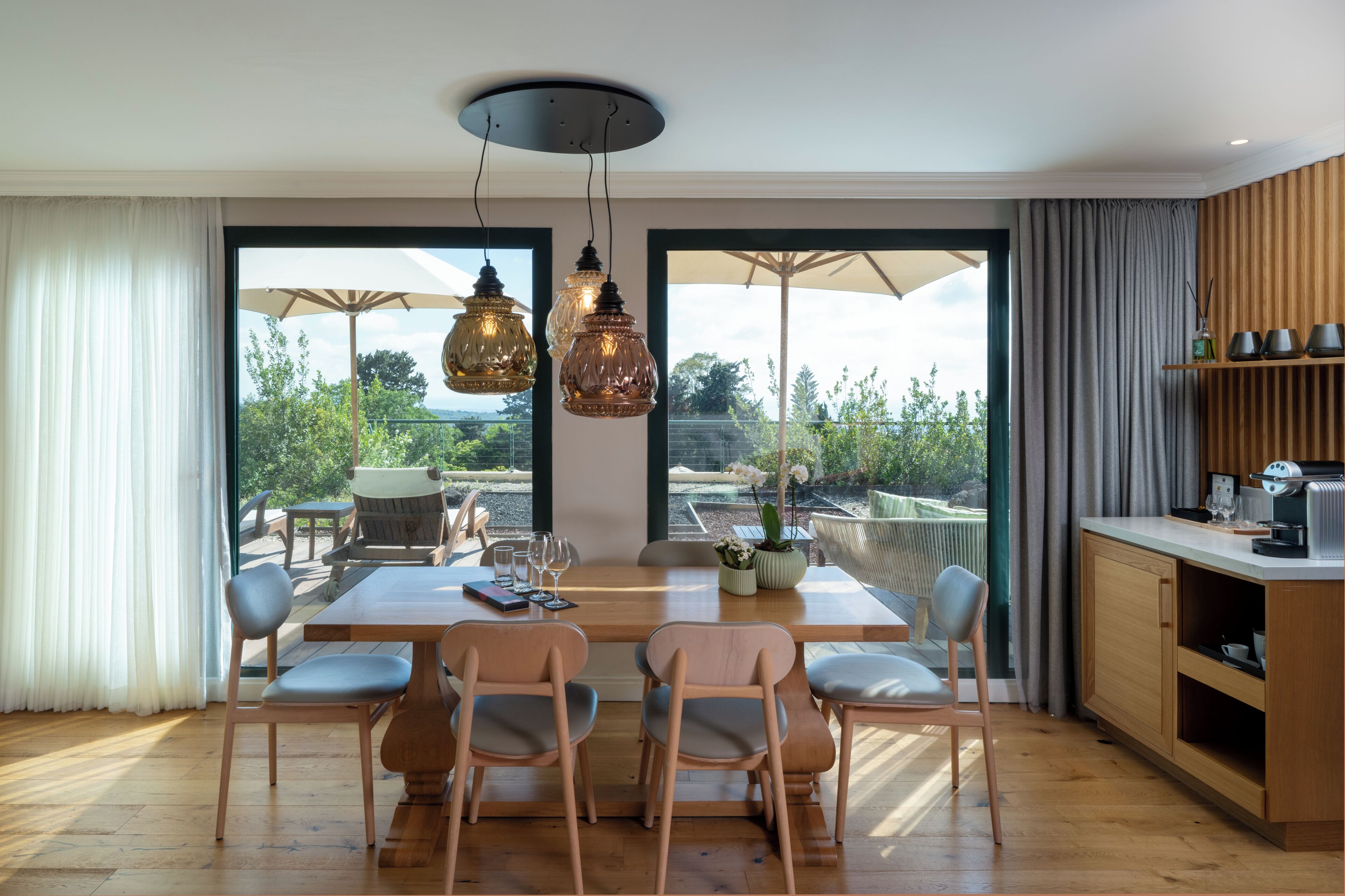 A dining area with a wooden table, chairs, and hanging pendant lights.