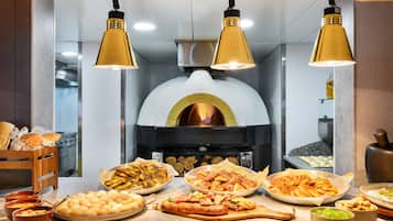A kitchen with a wood-fired oven, various baked goods, and cooking utensils.