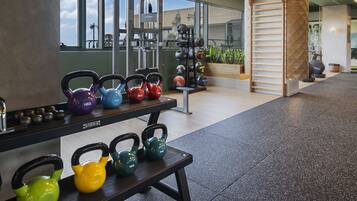 Ett gym med kettlebells, en bänk och annan träningsutrustning.