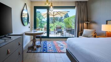 A hotel room with a bed, a television, a desk, and a view of the outdoors.