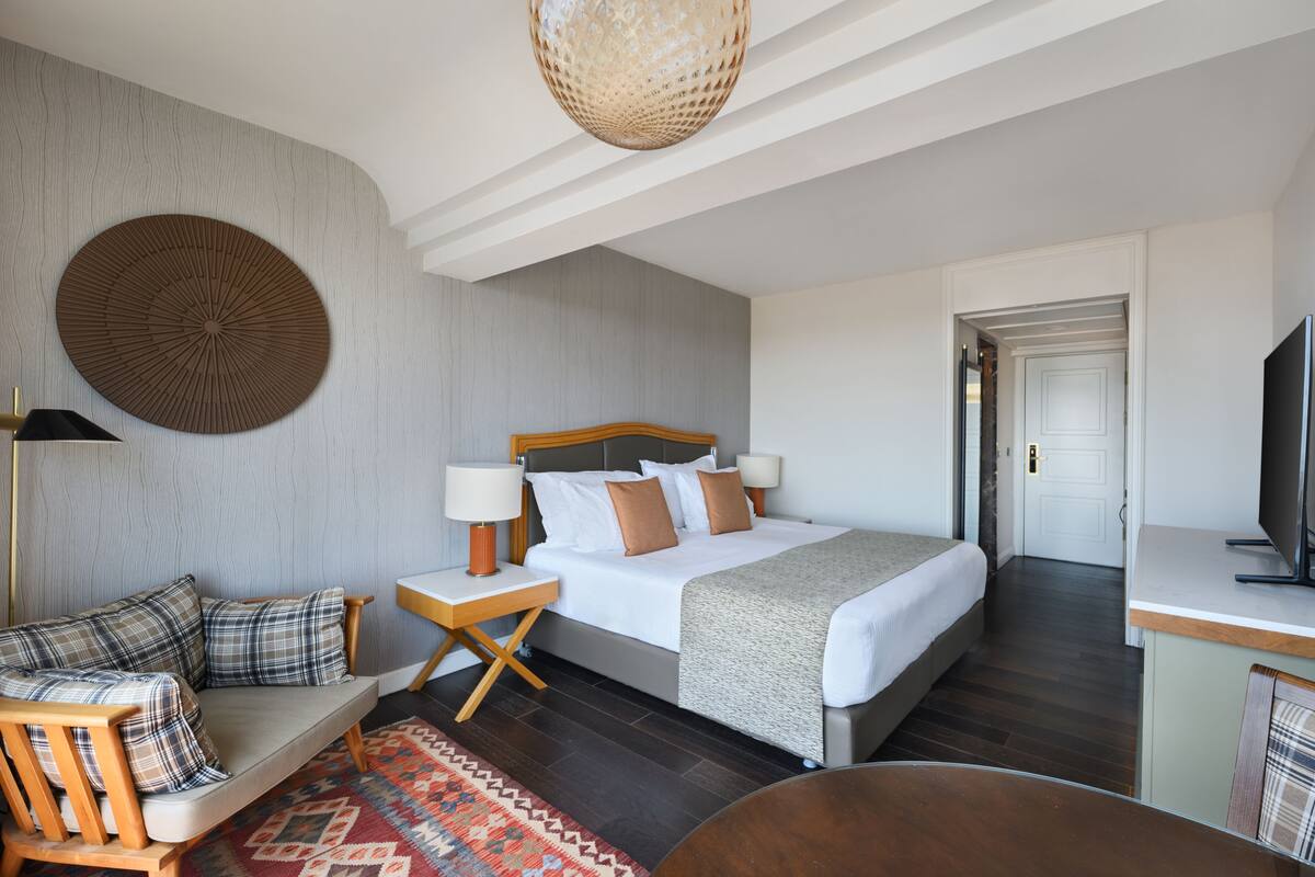 Ein modernes Hotelzimmer mit einem großen Bett, einer Couch, einem Schreibtisch und einem Fernseher.
