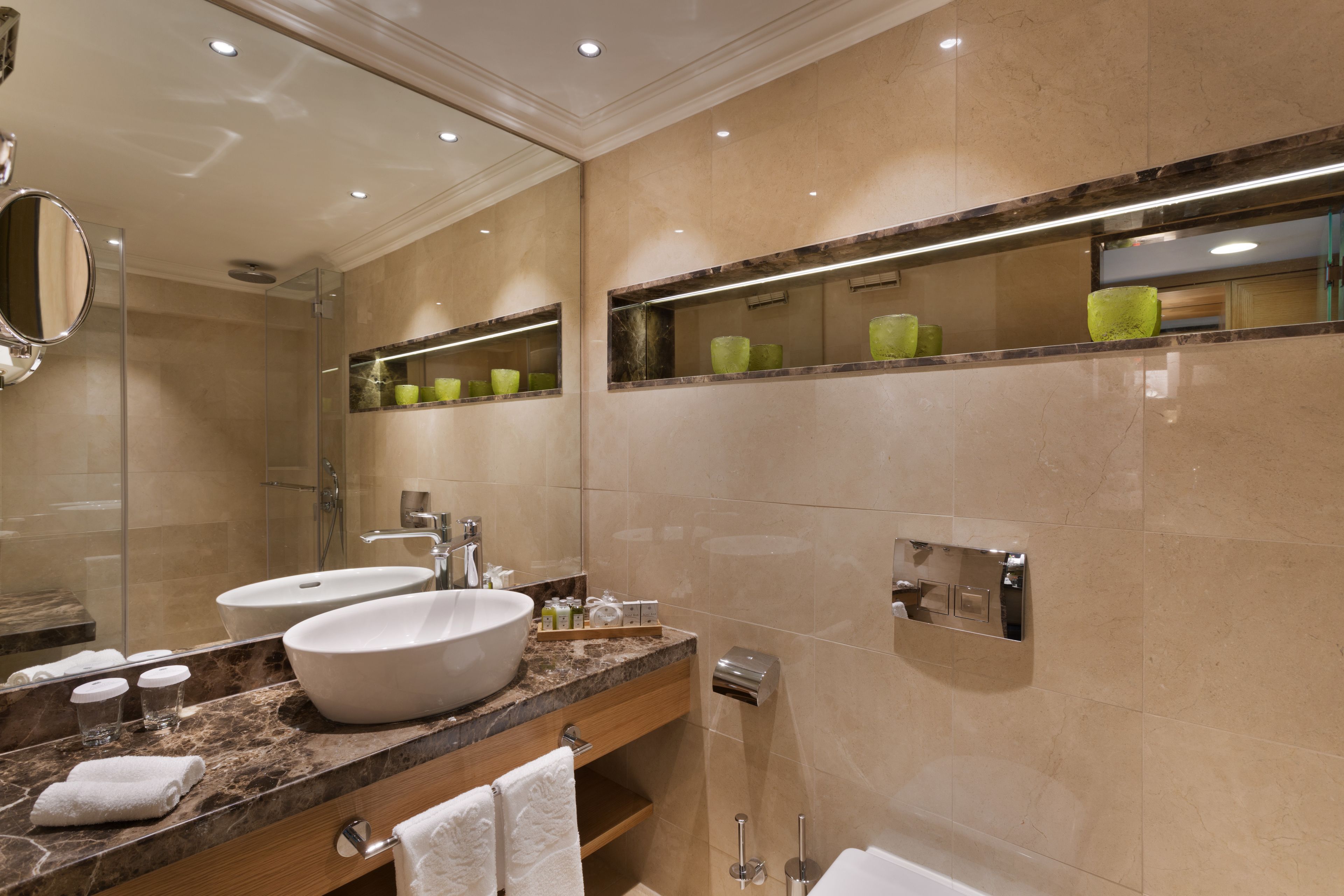 A modern bathroom with two sinks, a large mirror, and a glass shower enclosure.