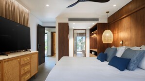 Une chambre à coucher moderne avec un grand lit, un téléviseur à écran plat posé sur une commode en bois et un ventilateur de plafond.