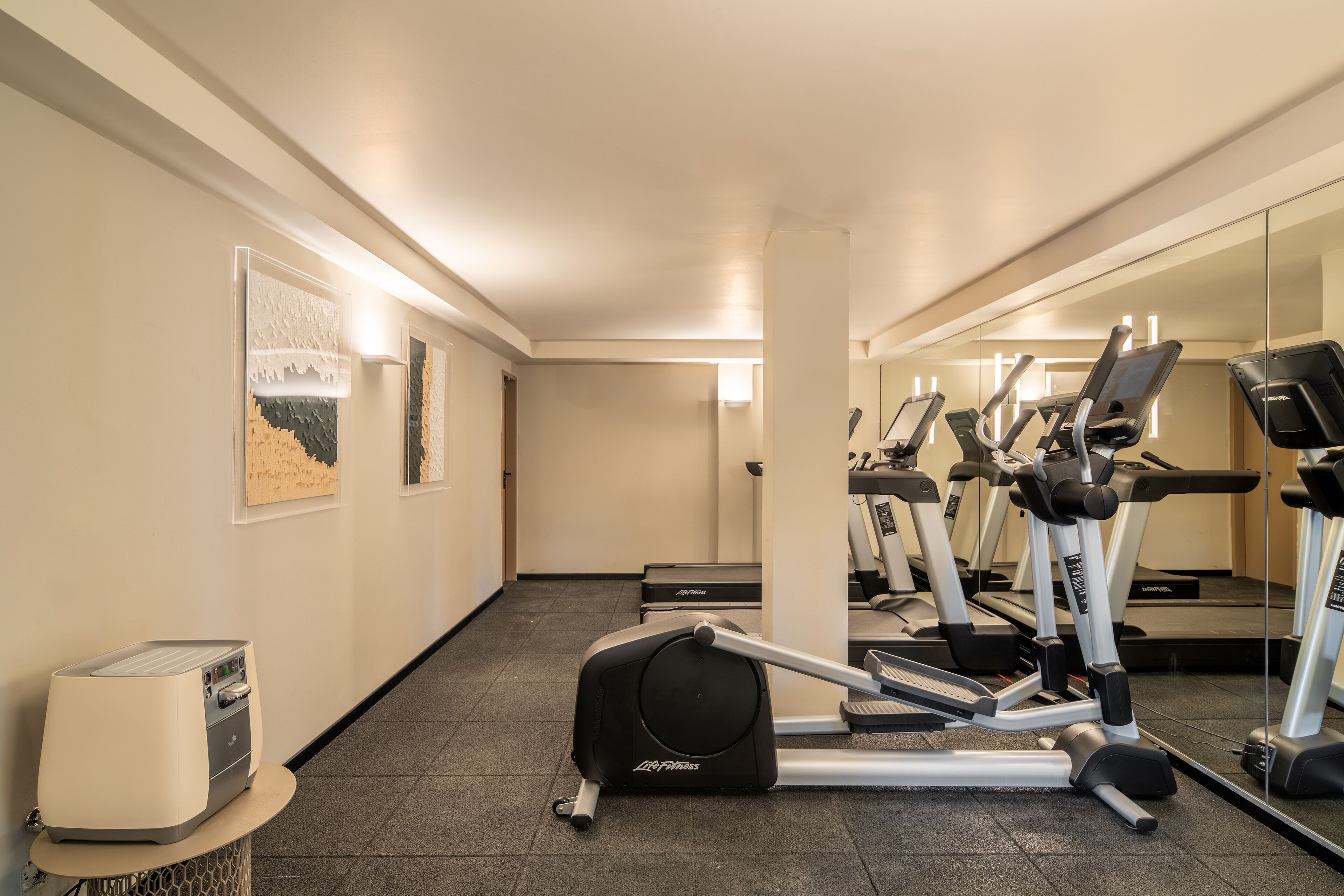Un gimnasio con cintas de correr, una bicicleta estática y una máquina de remo.