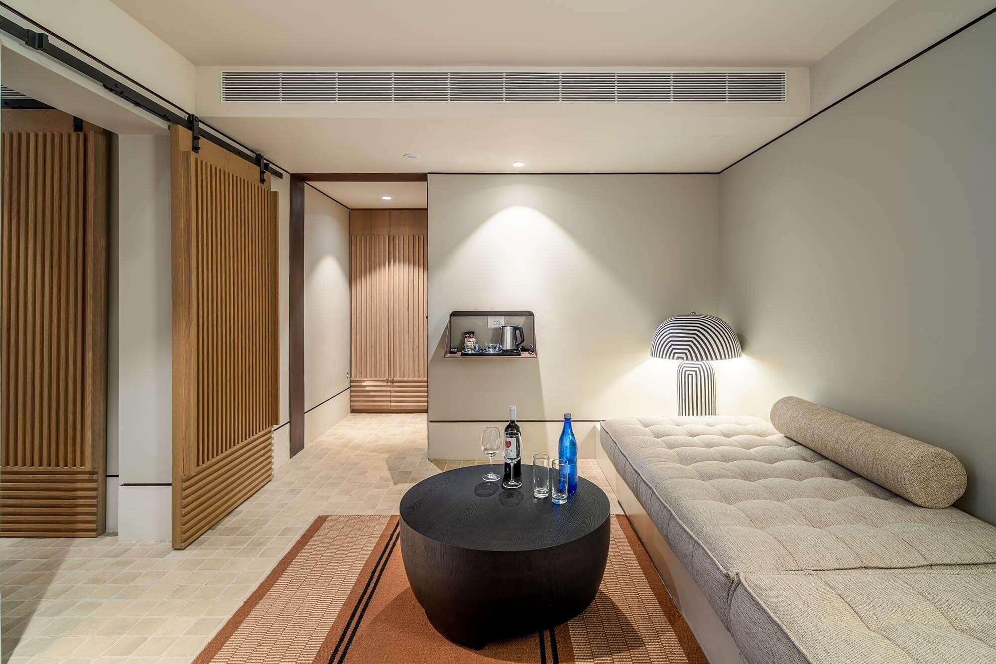 A modern living room with a sofa, a round black coffee table, and a lamp.