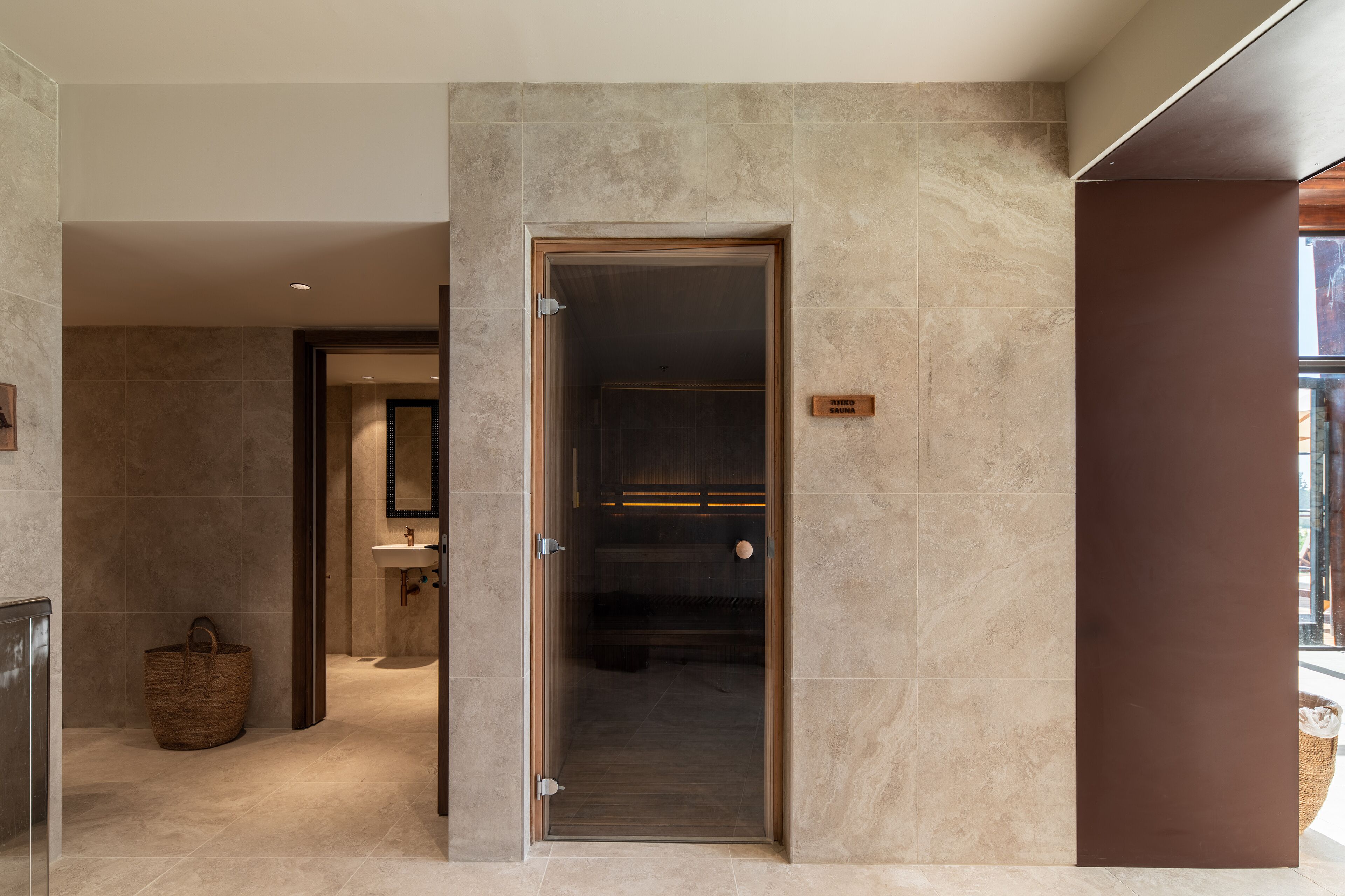 Une salle de bain moderne avec une porte de douche en verre, une porte en bois et un porte-serviettes visible.