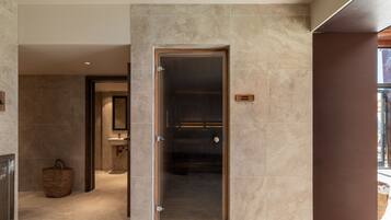 Un baño moderno con mampara de vidrio, puerta de madera y un toallero visible.