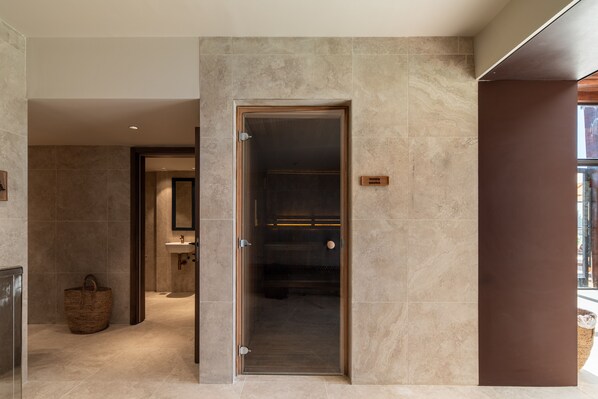Une salle de bain moderne avec une porte de douche en verre, une porte en bois et un porte-serviettes visible.