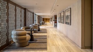 A corridor with seating areas, wooden partitions, and framed artwork on the walls.