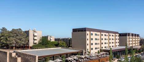 A hotel with a rooftop terrace, outdoor seating area, and a parking lot.