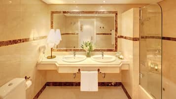 Une salle de bain moderne avec deux lavabos, un grand miroir, une douche en verre et des toilettes.