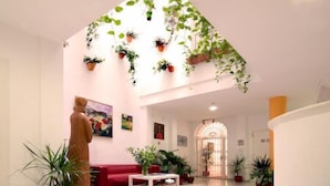 A spacious living area with a red sofa, a coffee table, and multiple potted plants. - Hotel Un Patio en Santa Cruz (Seville)