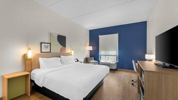 Een hotelkamer met een bed, bureau, televisie en een raam.