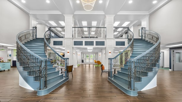 A spacious interior with a central staircase, a chandelier, and a view to the outdoors. - Spark by Hilton Tuscumbia Muscle Shoals (Tuscumbia)