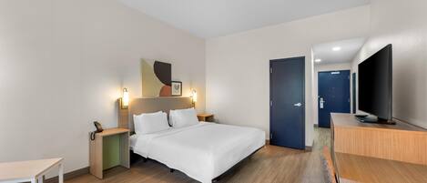 Una habitación de hotel moderna con cama, mesita de noche, televisor y escritorio.