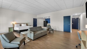 A hotel room with a bed, sofa, armchair, small table, and a desk. - Spark by Hilton Tuscumbia Muscle Shoals (Tuscumbia)