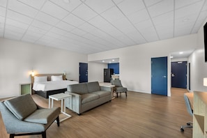 A hotel room with a bed, sofa, armchair, small table, and a desk. - Spark by Hilton Tuscumbia Muscle Shoals (Tuscumbia)