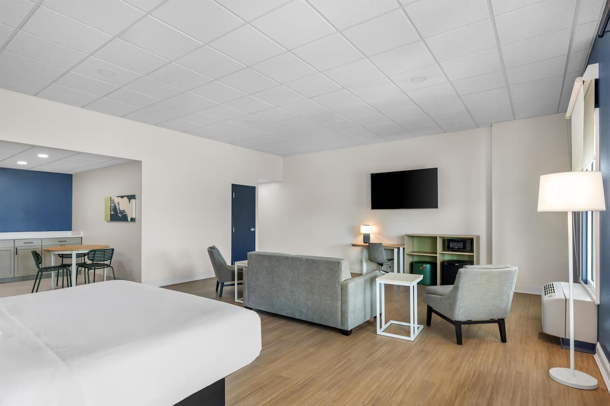 Una habitación de hotel con cama, sofá, escritorio, silla, televisor y lámpara.