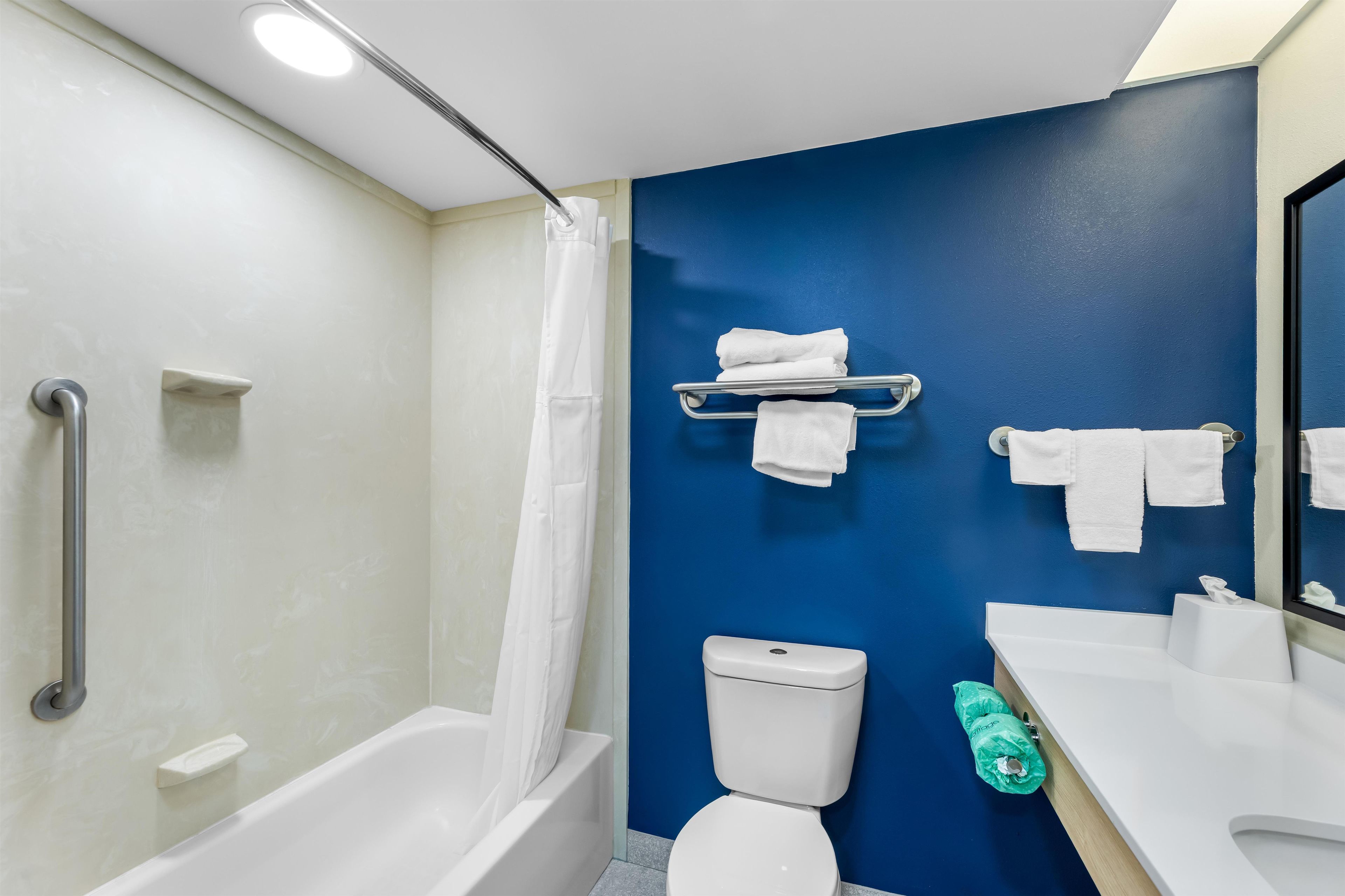 Een badkamer met een douche, toilet en wastafel, handdoeken hangen aan de muur.