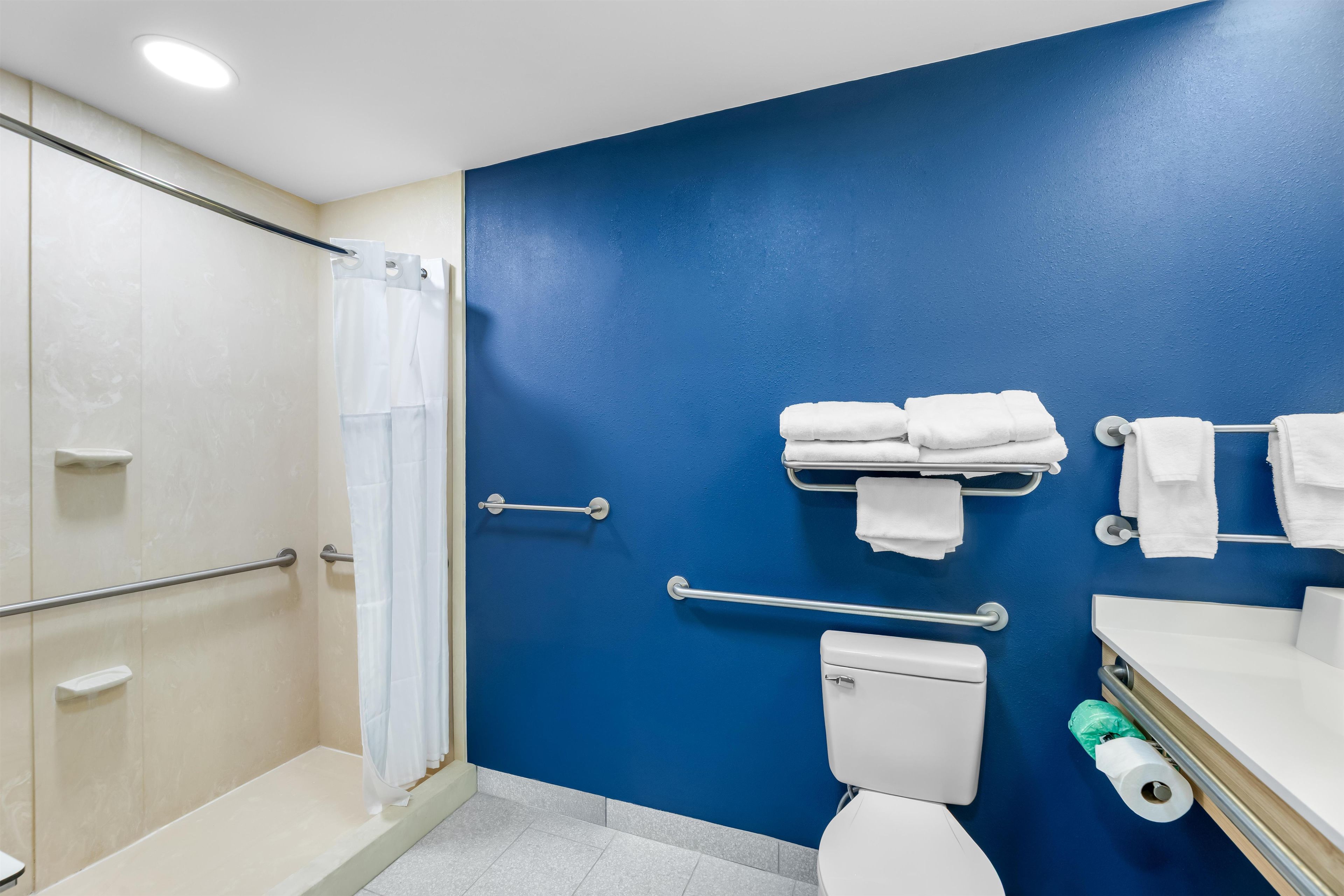 A bathroom with a blue wall, a white toilet, a shower with a glass door, and a towel rack.