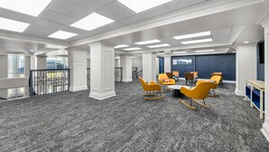 A spacious conference room with a high ceiling, large windows, and a grey carpet. - Spark by Hilton Tuscumbia Muscle Shoals (Tuscumbia)