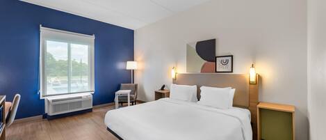 Een hotelkamer met een groot bed, een bureau, een stoel, een raam en een kunstwerk aan de muur.