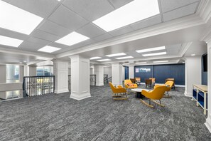 A spacious conference room with a high ceiling, large windows, and a grey carpet. - Spark by Hilton Tuscumbia Muscle Shoals (Tuscumbia)