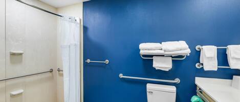 A bathroom with a blue wall, a white toilet, a shower with a glass door, and a towel rack.